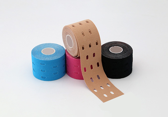 Colorful rolls of perforated kinesiology tape in different colors, with one tan strip unrolled showing evenly spaced oval holes