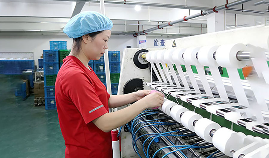 Workers inspecting kinesiology tape production machine in sports tape factory